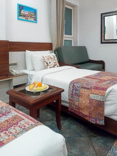 a hotel room with two beds and a table with a plate of oranges at Sterling Marbella Dehradun in Dehradun