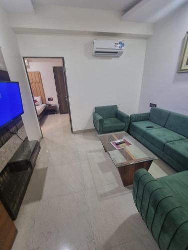 a living room with a green couch and a tv at Hotel Ranjeet Akola in Akola
