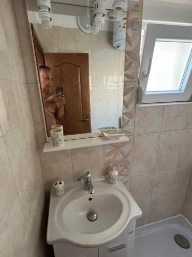 a man taking a picture in a bathroom mirror at SNG Apartmani in Brca