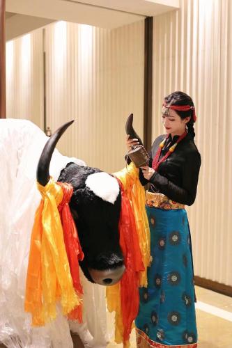 a woman standing next to a statue of a cow at Chengdu Tibetan Hotel-Free Welcome Tibetan Tea in Chengdu