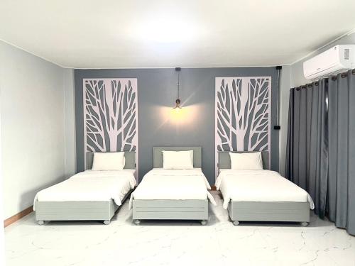 a bedroom with two beds with white sheets at Chainatgrand Hotel in Ban Khung Mae Luk On