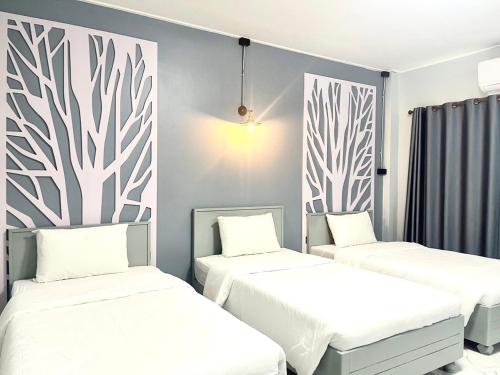two beds in a room with white walls at Chainatgrand Hotel in Ban Khung Mae Luk On