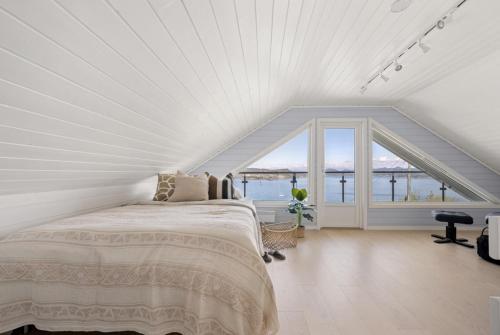 a white bedroom with a bed and a large window at The Green Bay in Sandnes