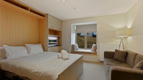 a bedroom with a bed and a couch and a window at Chalet Hotham 8 in Mount Hotham