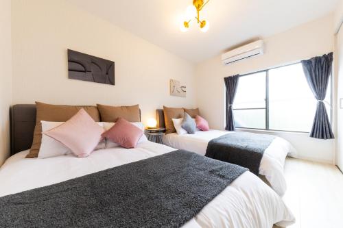 a bedroom with two beds and a window at 一棟貸切 Kuromon 3BedsRoom Doutonbori in Osaka