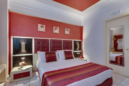 a bedroom with a large bed with a red wall at Fazio Rooms in Sciacca
