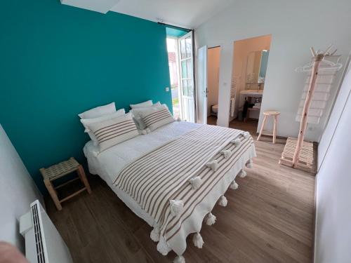 une chambre avec un grand lit avec un mur bleu dans l'établissement Escale Aixoise chambre privé, centre bourg, 50m de la mer, à Île-d'Aix