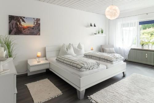 a white bedroom with a bed and a window at Buchen Blick - Ruhige moderne Ferienwohnung 82qm. in Fichtelberg