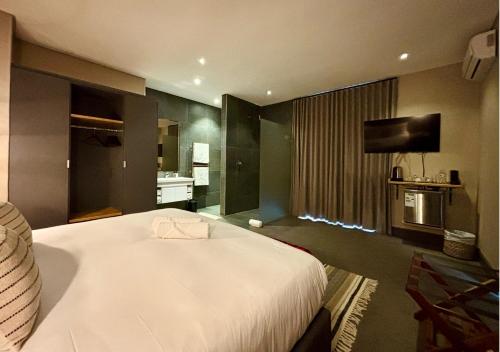a bedroom with a large white bed and a television at Blix Inn Guesthouse in Stellenbosch