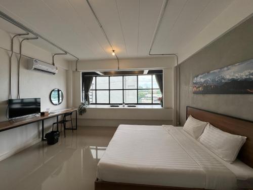 a bedroom with a bed and a desk and a window at Luka House in Lam Luk Ka