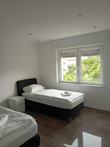 ein Schlafzimmer mit zwei Betten und zwei Fenstern in der Unterkunft Monteurwohnungen Distelfeld in Saarbrücken