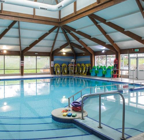 una grande piscina coperta con palestra con sedie gialle di Meadowside Caravan Hire Haven Kent Coast ad Allhallows