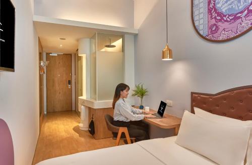 a woman sitting at a desk with a laptop at lyf Bugis Singapore managed by The Ascott Ltd in Singapore