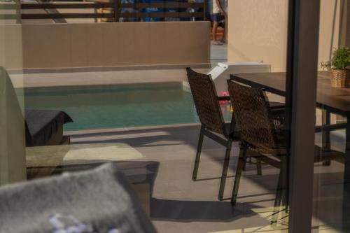 a table and chairs next to a swimming pool at Ntinas Seaside Suites in Skala Potamias