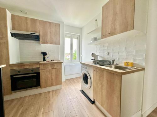une cuisine avec un évier et une machine à laver dans l'établissement L'Omega, lumineux & cosy, à Limoges