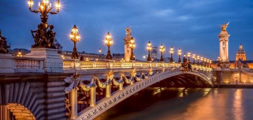 a bridge over a river with lights on it at BEST CENTRAL Chambres Privées - Seine & Louvre in the Connected Heart of Paris in Paris
