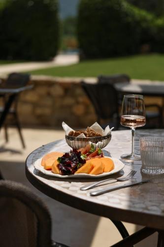 a table with a plate of food and a glass of wine at Château Les Oliviers de Salettes in Charols