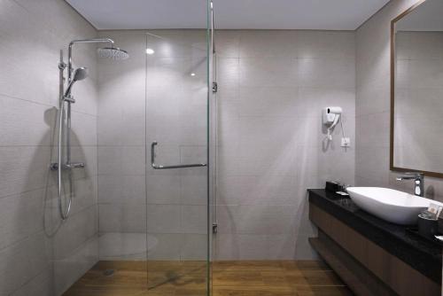 a bathroom with a glass shower and a sink at Harper Premier Nagoya Batam in Nagoya