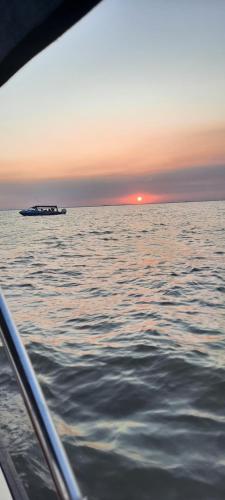 a boat in the ocean with a ship in the distance at Casa orizont in Sulina