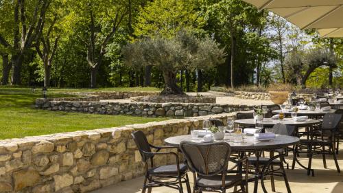 a restaurant with tables and chairs and a stone wall at Château Les Oliviers de Salettes in Charols