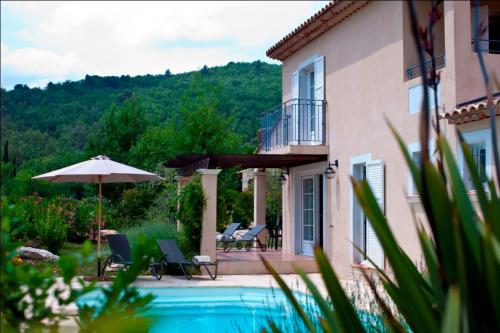 a house and a swimming pool with chairs and an umbrella at Callian - Très belles Villas, 3 chambres et piscine privée in Callian