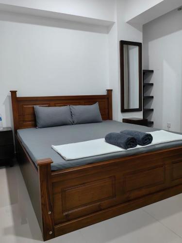 a bed with a wooden frame and a mirror at Oval View by CityScape in Colombo