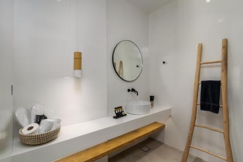 a white bathroom with a sink and a mirror at Arco Solium Suites in Adamas