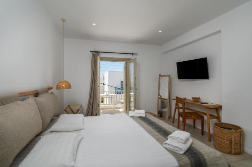 a bedroom with a large white bed and a desk at Arco Solium Suites in Adamas