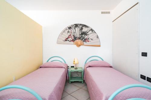 Dos camas en una habitación pequeña con una mesa. en Confortevole e fresco seminterrato, en Siniscola