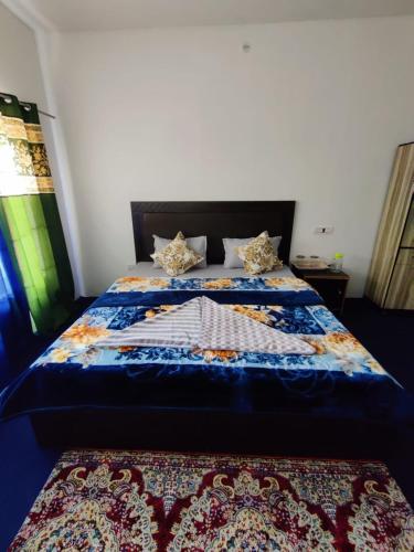 a bed with a blue comforter and two pillows at Nubra Holiday in Deskit