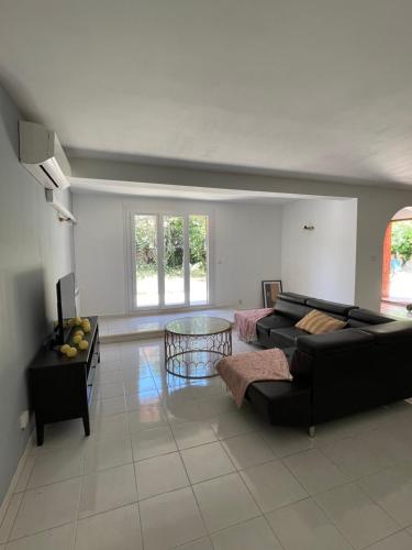 un salon avec un canapé noir et une table dans l'établissement Bas de villa Hippolyte et Marguerite CLIM, aux Pennes-Mirabeau