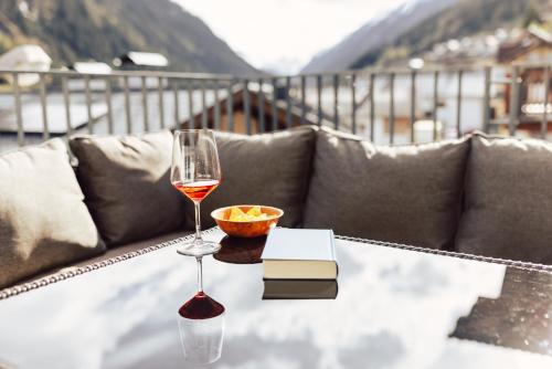 a glass of wine and a book on a table at Ferienwohnen Mattle MIT IM RUCKSACK die SILVRETTA CARD PREMIUM in Kappl