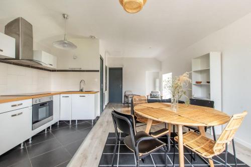 une cuisine et une salle à manger avec une table et des chaises en bois dans l'établissement Casa Sequoia – Appart’, à Bouchemaine