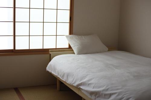 a small bedroom with a white bed and a window at Kyomachiya Daitokuji in Kyoto