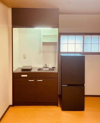 a kitchen with a black refrigerator and a sink at Kyomachiya Kitayamaomiya in Kyoto