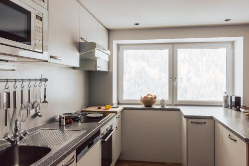 a white kitchen with a sink and a window at Ferienwohnen Mattle MIT IM RUCKSACK die SILVRETTA CARD PREMIUM in Kappl