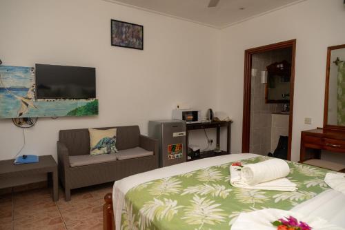 a bedroom with a bed and a couch and a tv at Pension Hibiscus in La Digue