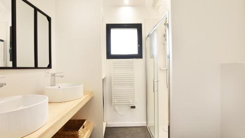 une salle de bain blanche avec un lavabo et une fenêtre dans l'établissement Maison 4 chambres, Petit Piquey, à Lège-Cap-Ferret