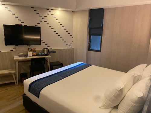 a bedroom with a bed and a desk and a television at Salee Boutique Hotel in Chiang Mai