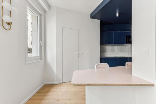 une cuisine avec un comptoir blanc et des armoires bleues dans l'établissement Art et Confort près de la Bastille by Weekome, à Paris