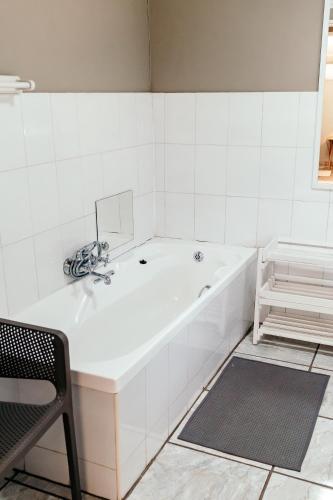 a white bathroom with a tub and a chair at Misty Morn Cottages in Muldersdrift