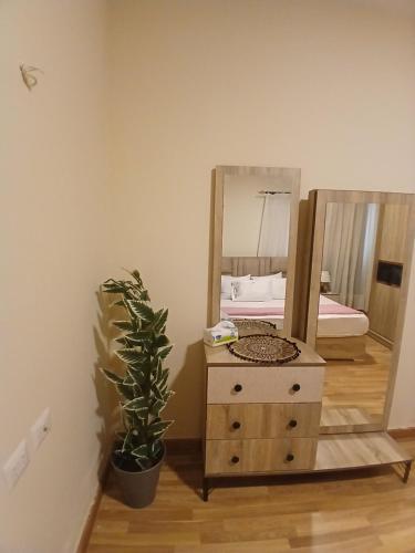 a dresser with a mirror and a plant in a room at Luxerious apartment with a private garden and pool access in Sheikh Zayed