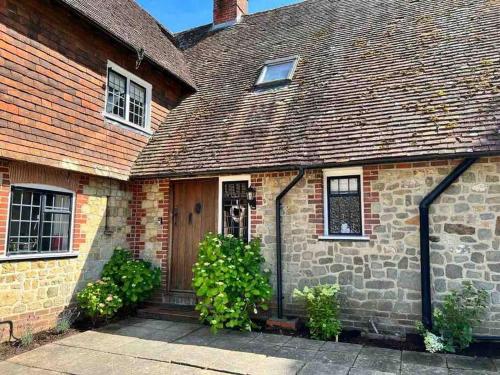 an old brick house with a wooden door at Picturebook cottage on prestigious polo estate in Stedham