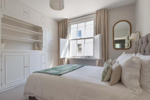 a white bedroom with a large bed and a mirror at Victory Cottage in Lymington