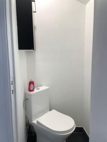 une salle de bain avec des toilettes blanches et un réveil rouge dans l'établissement #7 Appartement pour 5 personnes près du métro L9, à Bagnolet