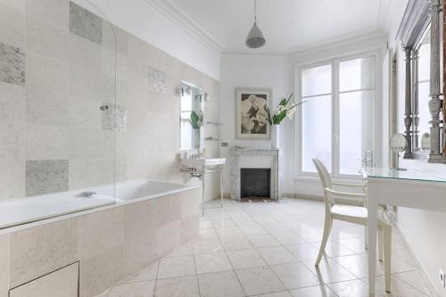 La salle de bains blanche est pourvue d'une baignoire et d'une cheminée. dans l'établissement Invalides Pont Alexandre III Luxury Apartement 2BR, à Paris