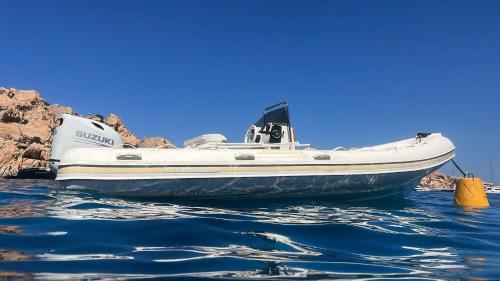 a boat sitting in the water next to some rocks at Il Maestrale in La Maddalena