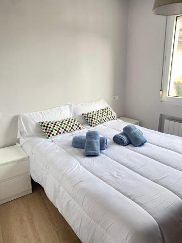 a large white bed with two blue pillows on it at Mundaka plaza in Mundaka