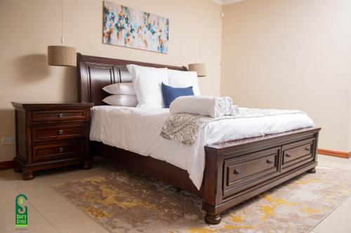 a bedroom with a bed and a nightstand with pillows at Su's Crest in Blantyre
