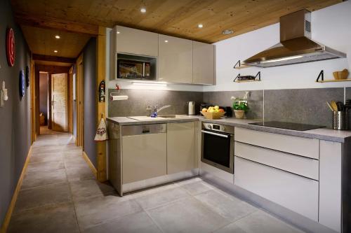 a kitchen with white cabinets and a sink at Le Petit Capricia - OVO Network in La Clusaz
